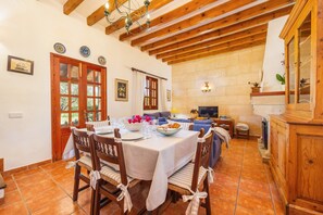 A dining area with a table set for four, wooden chairs, a fireplace, and a television.