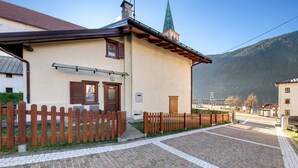 Ein Gebäude mit Holzzaun, gepflastertem Innenhof und einem Berg im Hintergrund.