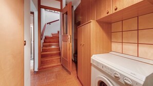 Ein Waschbereich mit Waschmaschine, Holzausstattung und einer Treppe.