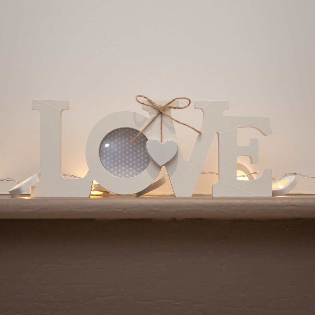 Een plank met verlichte letters die 'LOVE' spellen en een hartvormige decoratie.