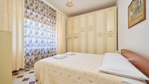Un dormitorio con cama, cortinas, armario y un cuadro en la pared.
