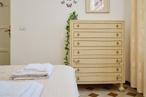 Quarto com cama, cómoda, tomada, quadro emoldurado e cortina.
