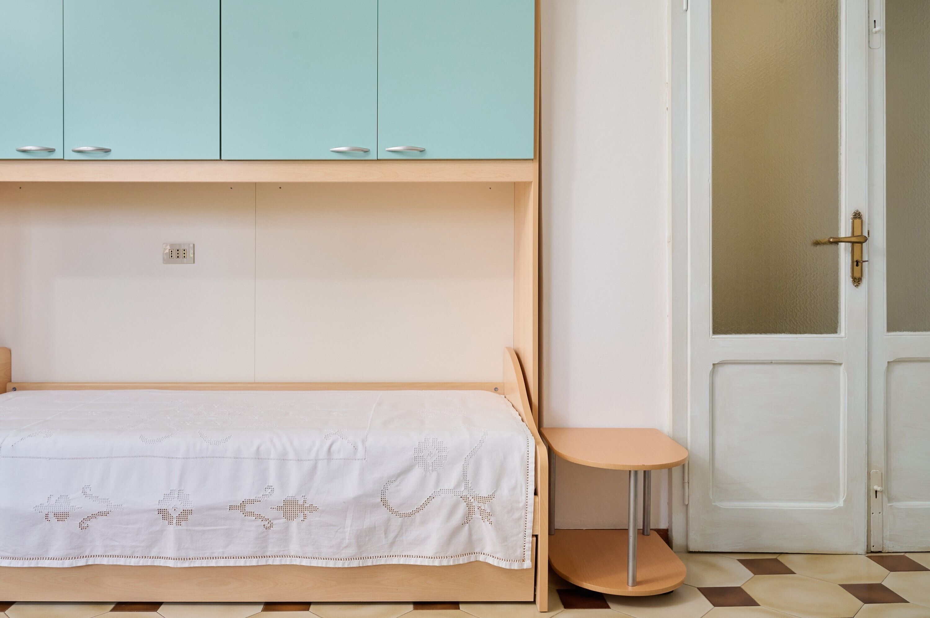 Une chambre à coucher avec un lit, une petite table, une armoire et une porte.