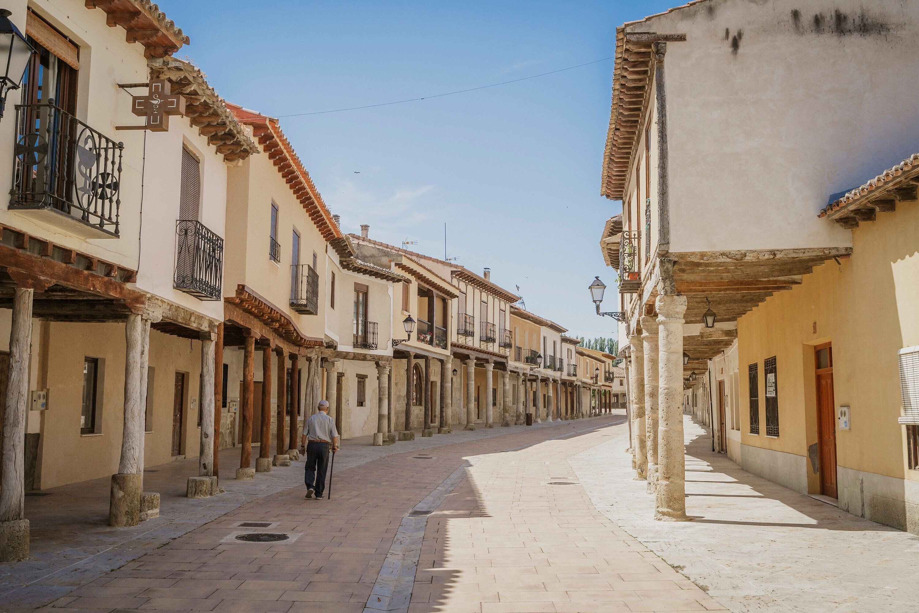 A street with buildings, a man walking, and a clear sky.