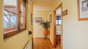 Un pasillo con un radiador, una planta en maceta, cuadros enmarcados y un cartel en la pared.