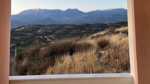 Blick aus einem Fenster auf eine gebirgige Landschaft mit Feldern und spärlicher Vegetation.