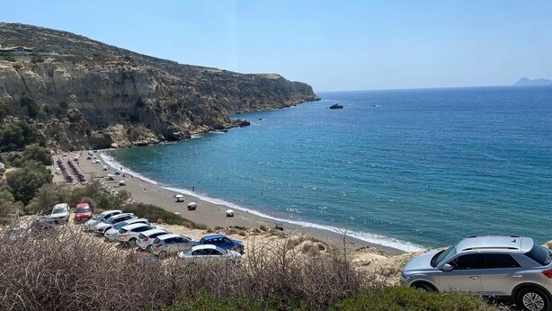 Eine Küstenstraße mit geparkten Autos und einem Strand.