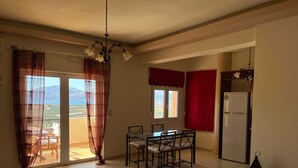 Ein Essbereich mit Tisch und Stühlen, einem Kühlschrank und Blick durch ein Fenster.