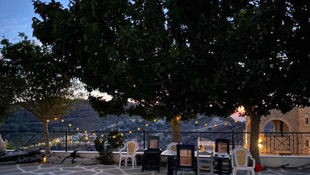 An outdoor seating area with tables and chairs, a dog, and a stone floor. - Apartment 'Spitiko  1' with Sea View, Shared Terrace and Wi-Fi (????????)