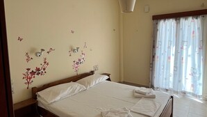 A bedroom with a bed, a nightstand, a wall-mounted light, and a window with curtains. - Apartment 'Spitiko  1' with Sea View, Shared Terrace and Wi-Fi (????????)