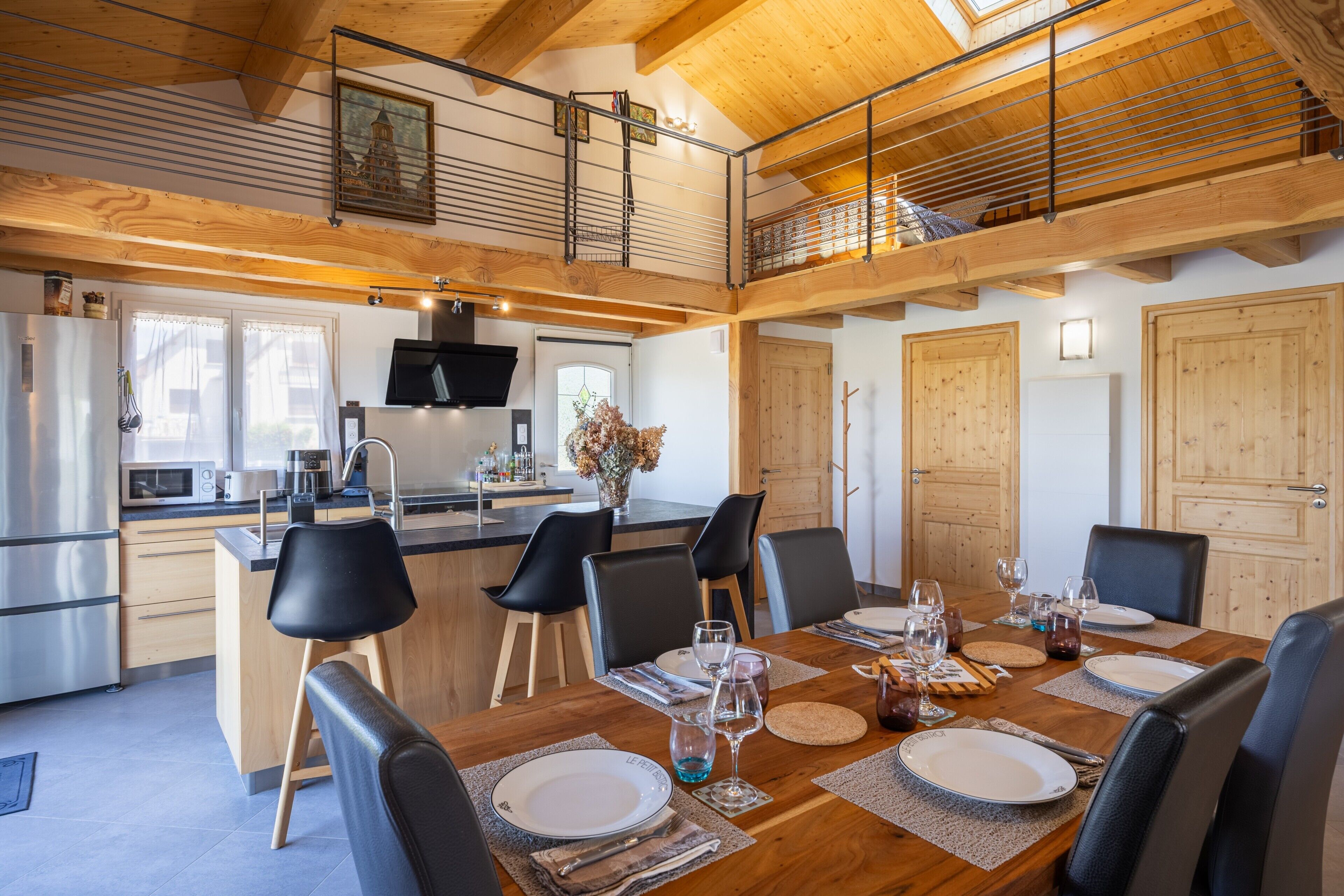 Una cocina moderna con comedor, vigas de techo de madera y vistas al exterior.