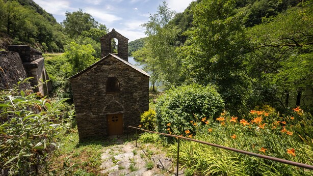 A stone building with a bell tower, surrounded by lush greenery and a river. - Holiday Home 'Maison Chalet' with Mountain View, Private Terrace and Wi-Fi (Le Nayrac)