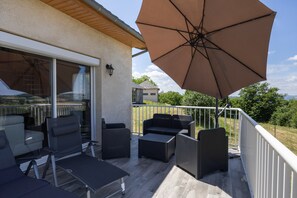 An outdoor patio with wicker furniture, a large umbrella, and a view of the surrounding landscape.