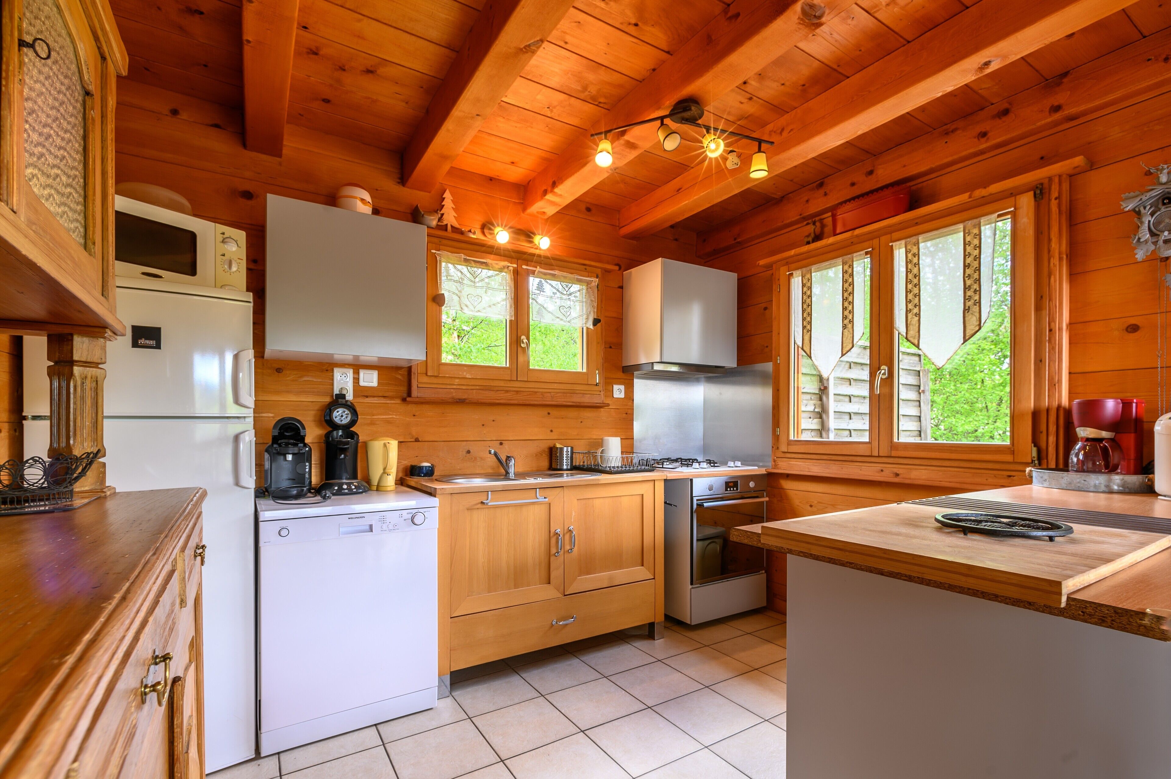 Eine Holzhütte mit einer Küche, inklusive Kühlschrank, Herd, Spüle und Schränken.