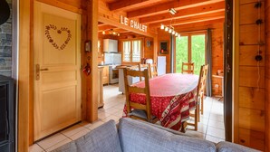Puinen mökki, jonka sisätiloissa on ruokailutila, keittiö ja ovi, joka on koristeltu sydänkuviolla.