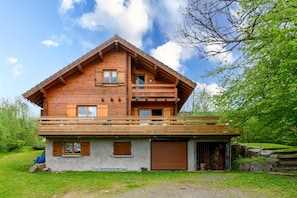 Un chalet en bois doté d’un balcon, d’un garage et de fondations en pierre.
