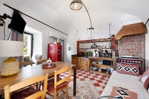 A kitchen with a red refrigerator, wooden cabinets, a brick wall, and a checkered floor. - Apartment 'Nespolo' with Sea View, Wi-Fi and Air Conditioning (Finale Ligure)