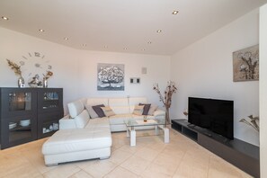 A modern living room with a sofa, coffee table, TV, and decorative items. - Holiday Home 'Appartamento Porto Pozzo' with Sea View, Wi-Fi and Air Conditioning (Porto Pozzo)