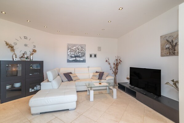 A modern living room with a sofa, coffee table, TV, and decorative items.