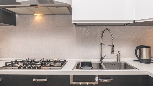 Una cocina moderna con estufa a gas, pileta de acero inoxidable y hervidor.