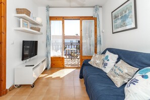 Ein Wohnzimmer mit Fernseher, Sofa und einem Balkon mit Blick.