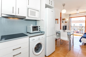 Eine kleine Küche mit Mikrowelle, Toaster, Waschmaschine und Kühlschrank.