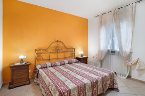 Ein Schlafzimmer mit einem Bett, Nachttischen und einem Fenster mit Vorhängen.