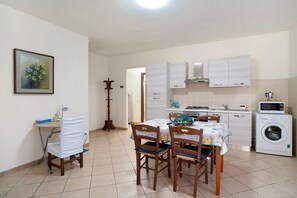 Cocina compacta con comedor, lavadora y mesa de comedor con sillas.