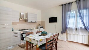 A modern kitchen with a dining table, chairs, and a TV mounted on the wall. - Villa 'Il Frutteto 50' with Private Terrace and Wi-Fi (Ortovero)
