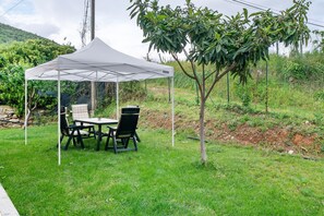 Ein weißes Zelt mit Tisch und Stühlen auf einer Rasenfläche.
