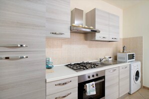 Una cocina moderna con estufa a gas, microondas, horno y lavadora integrada.
