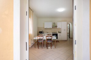 Une cuisine compacte avec des meubles blancs, une table à manger avec des chaises et un four à micro-ondes.