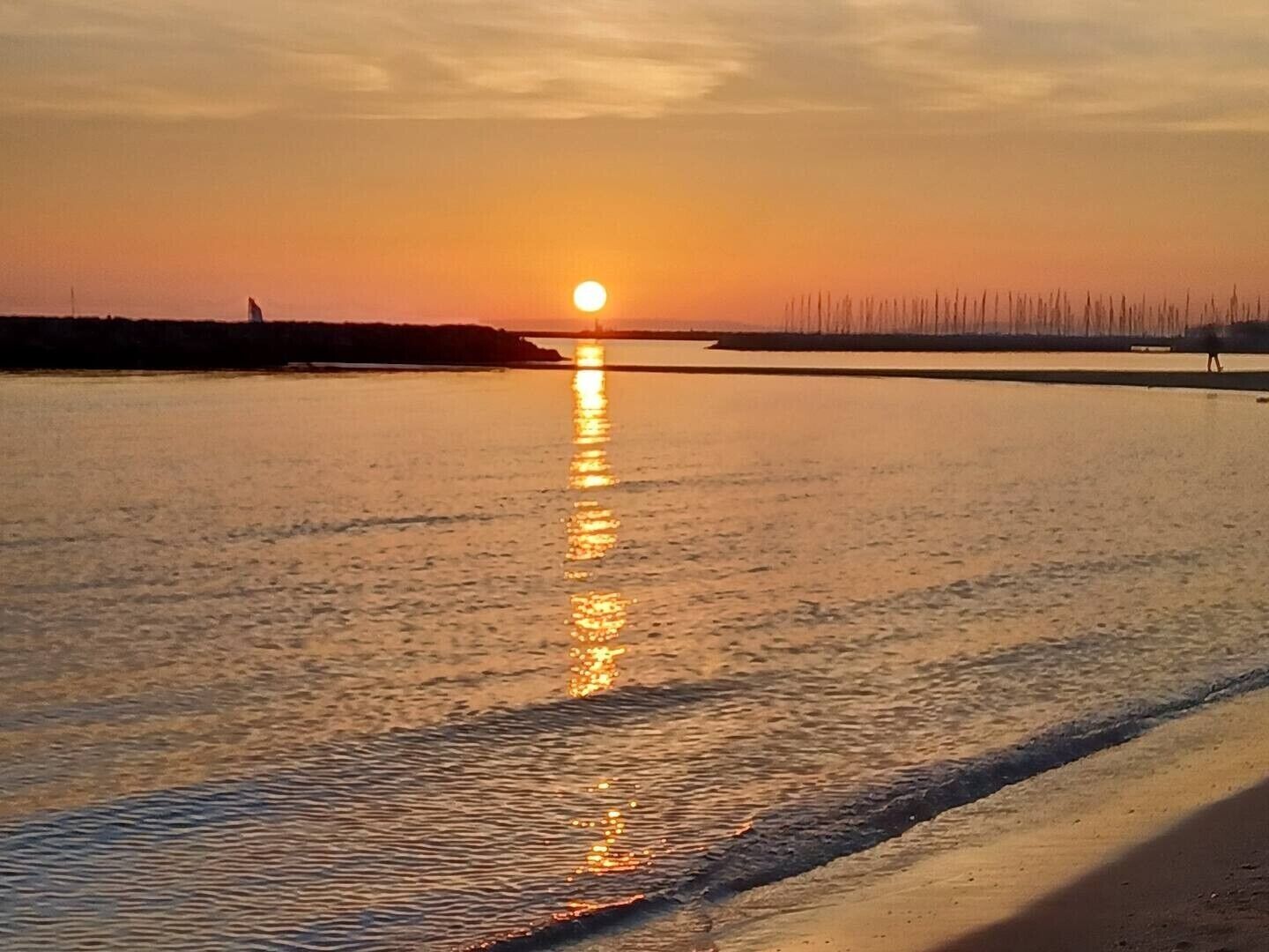 Atardecer sobre una masa de agua tranquila con una costa distante.