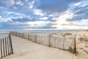 A sandy beach with a wooden fence, a clear sky, and the ocean in the background. - Studio 'Le Cozy A La Grande Pyramide' with Wi-Fi (La Grande-Motte)