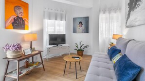 A modern living room with a sofa, a TV, a coffee table, and artwork on the walls.