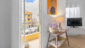 A modern living room with a balcony, a flat-screen TV, a painting, and a lamp.