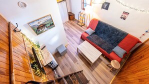 L’intérieur d’un chalet accueillant, avec un plancher en bois, un canapé, une petite table, une lampe et un tableau accroché au mur.