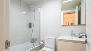 Ein modernes Badezimmer mit einer Duschkabine, einer Toilette und einem Waschbecken mit Spiegel darüber.
