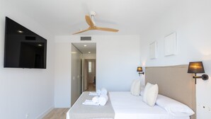 Ein Hotelzimmer mit einem großen Bett, einem Deckenventilator, einem Flachbildfernseher und zwei Wandlampen.