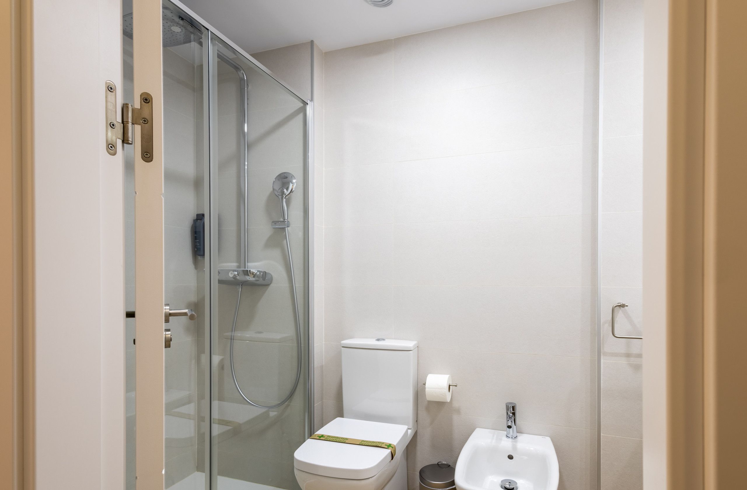 A compact bathroom with a glass-enclosed shower, a toilet, and a bidet.
