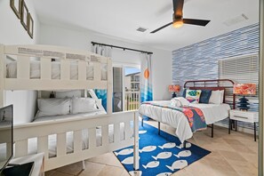 A bedroom with a bunk bed, a single bed, a desk, and a window with blinds. - Stunning waterfront home with private pier and sunset views - Buy 7 Nights, Get 1 Free! (Galveston)