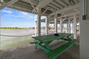 A green picnic table with benches under a white structure by a calm body of water. - Stunning waterfront home with private pier and sunset views - Buy 7 Nights, Get 1 Free! (Galveston)