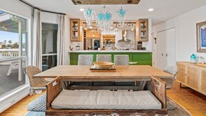 A dining area with a wooden table, wicker chairs, and a bench with cushions.