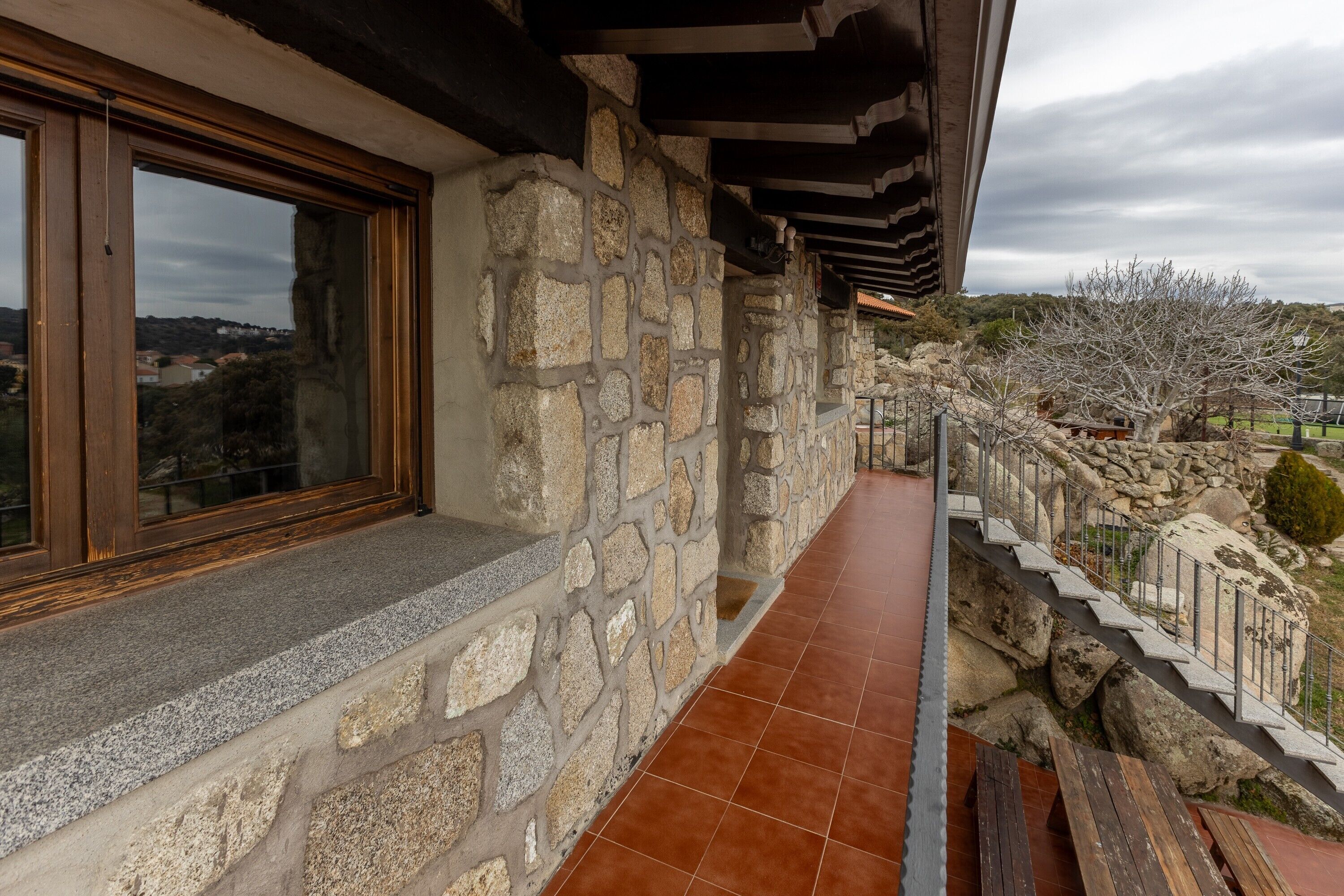 Fachada de piedra con una ventana, pared de piedra y terraza de madera.
