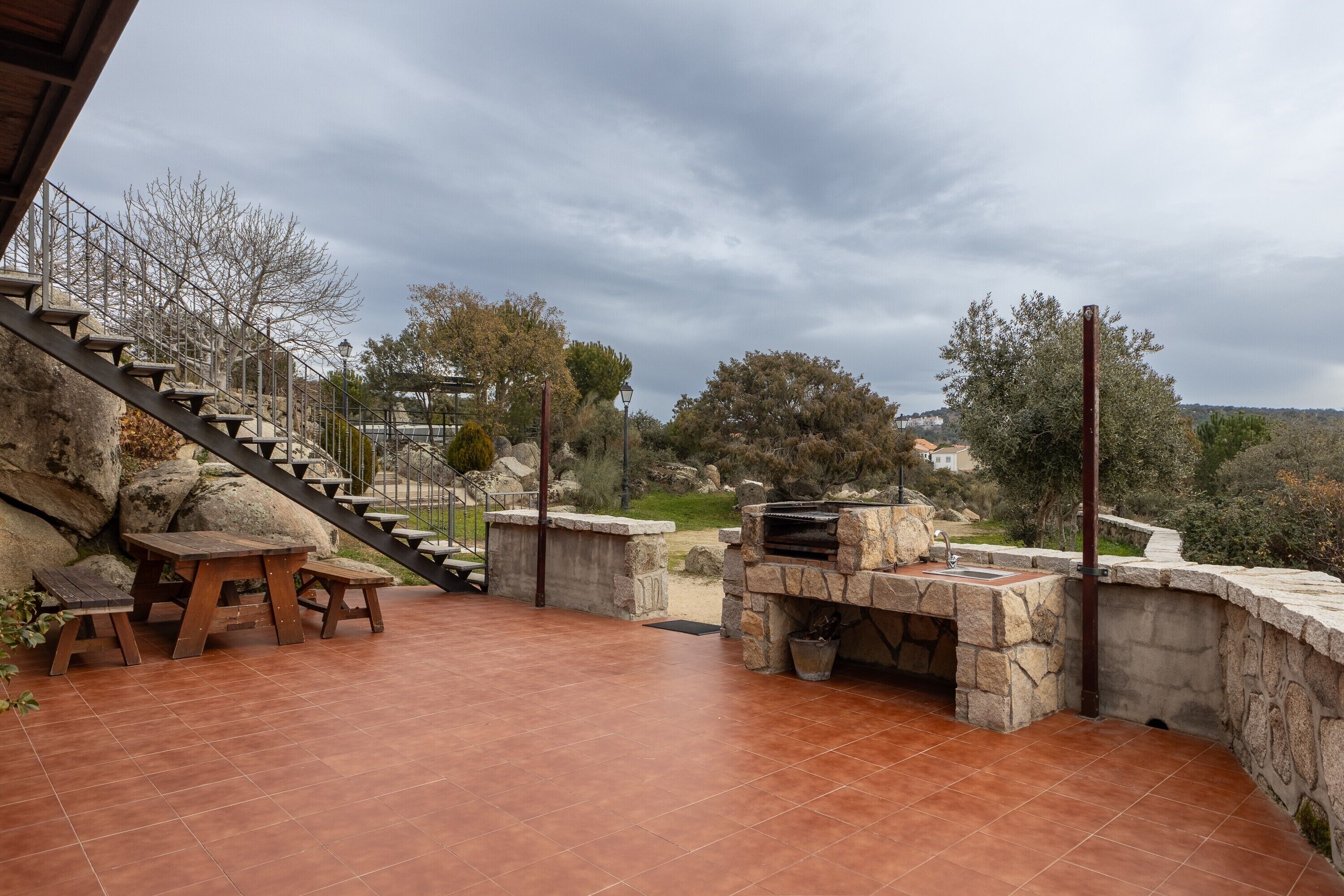 Une terrasse avec des marches en pierre, un barbecue et une table avec des bancs.