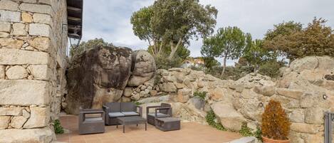A stone building with a patio area featuring outdoor furniture and a potted plant.