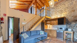 A spacious living area with a sofa, coffee table, and a staircase leading to an upper level. - Apartment 'Casa De Piedra' with Shared Pool, Private Terrace and Wi-Fi (Fresnedillas de la Oliva)