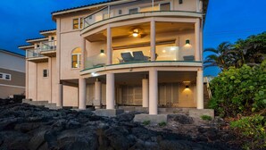 Une maison à plusieurs étages dotée d’un balcon incurvé, d’un porche abrité et d’un espace piscine.