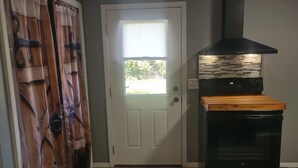 A kitchen with a black range hood, a wooden countertop, and a white door with a window. - Serenity's Sanctuary in this quiet, peaceful 2 bdr 1 bath bungalow. Pet friendly (Cushing)