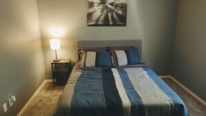 A bedroom with a bed, a nightstand, a lamp, and a painting on the wall. - Serenity's Sanctuary in this quiet, peaceful 2 bdr 1 bath bungalow. Pet friendly (Cushing)